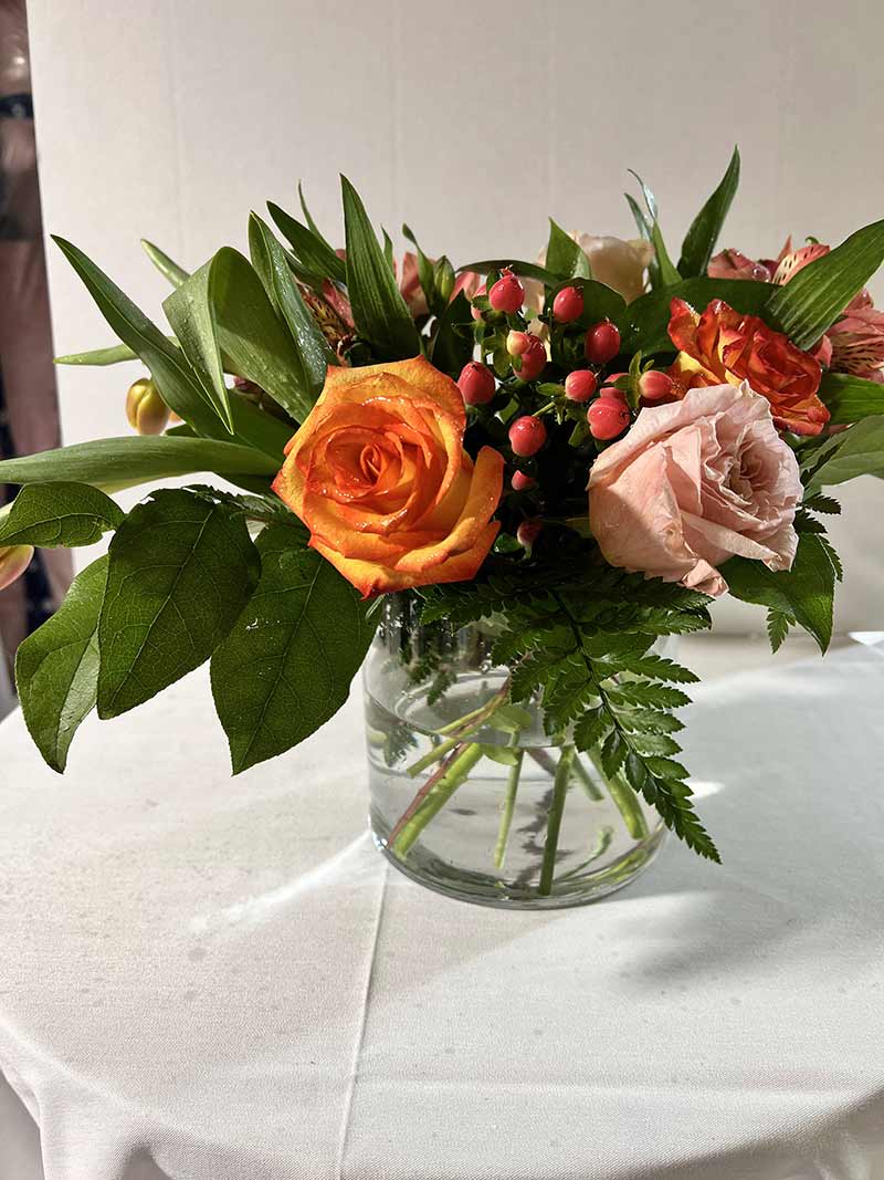 Orange and blush roses in a clear glass vase