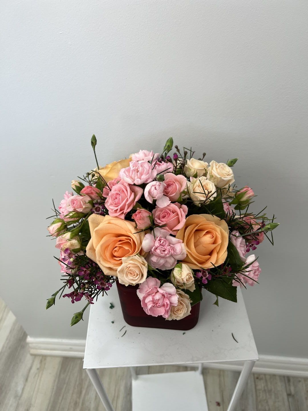 Pink and peach roses arranged in a burgundy box