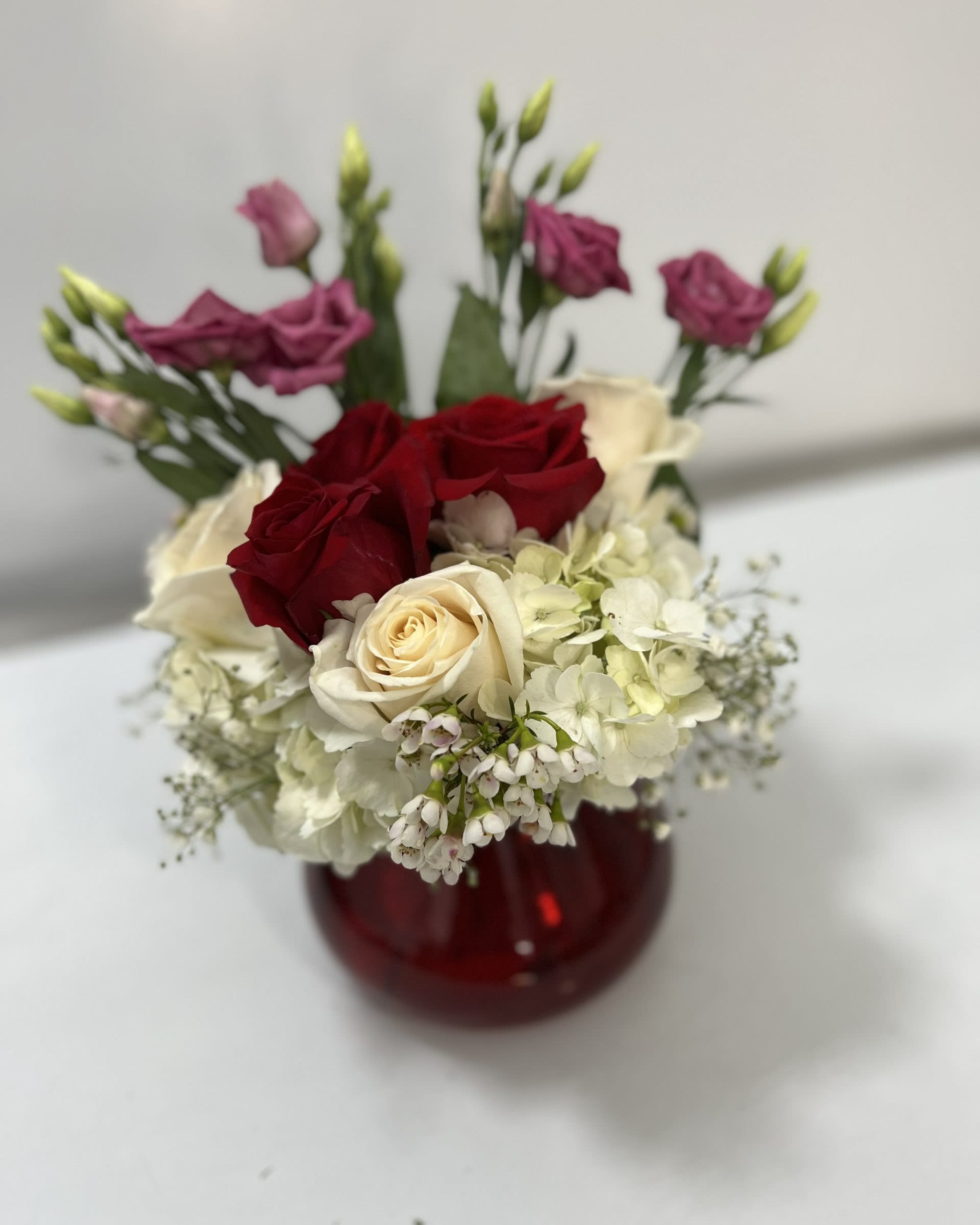 Red and cream roses with white hydrangea in a red vase