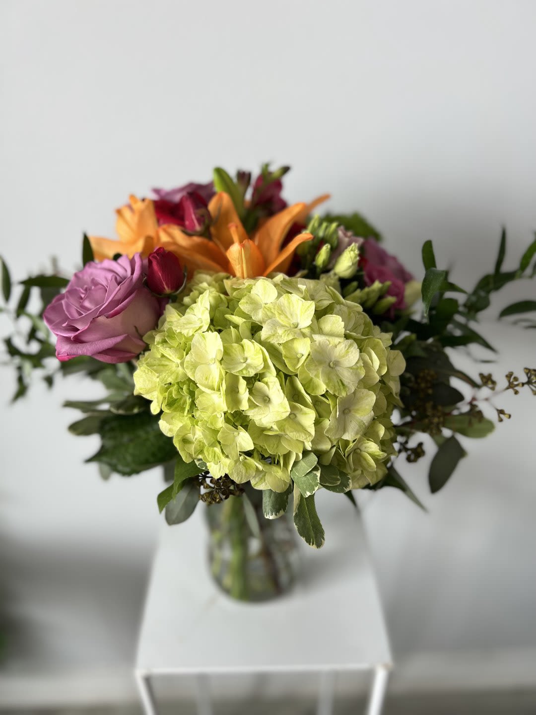 Bouquet of hydrangeas, roses, and lilies in a glass vase