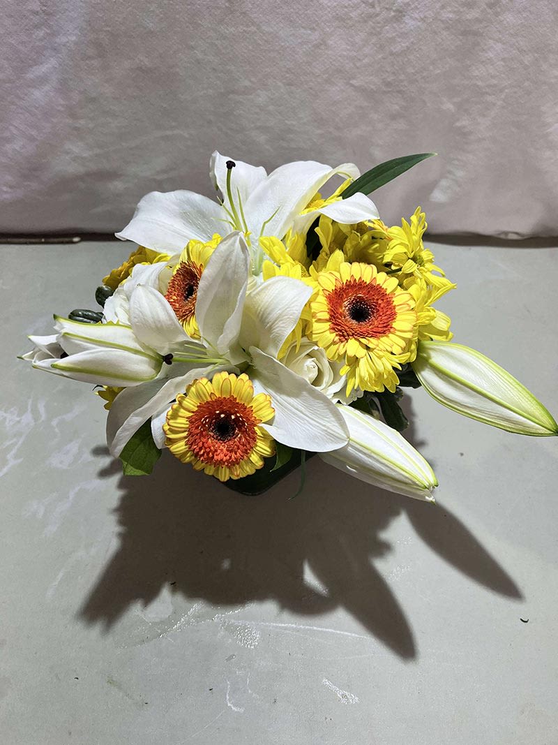White lilies and yellow gerbera daisies in a low arrangement