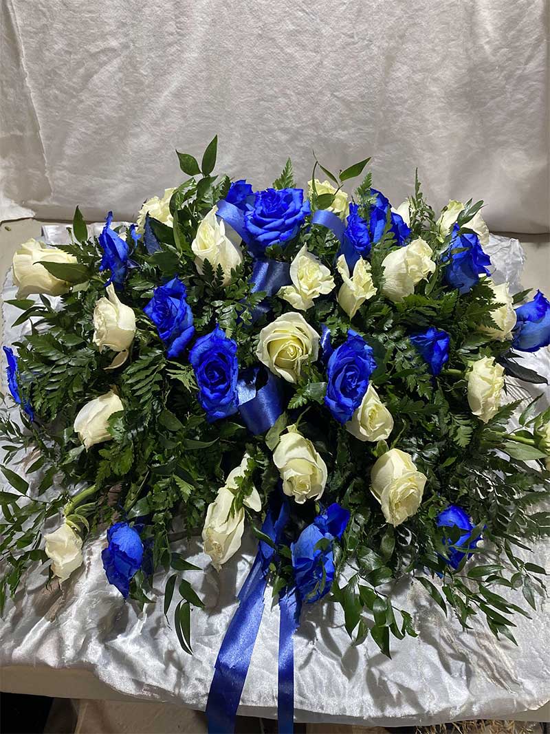 Blue and white rose arrangement with ribbon on satin fabric