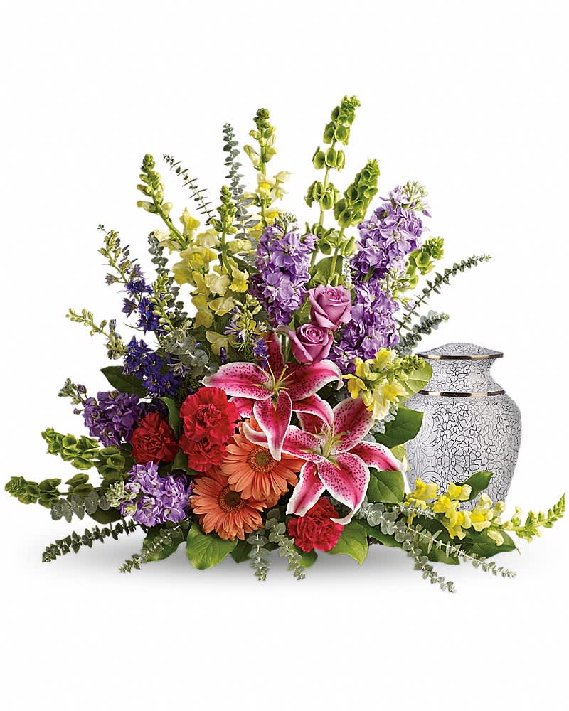 Mixed bouquet with lilies, roses, and purple flowers beside a patterned urn