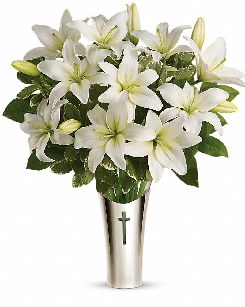 White lilies arranged in a silver vase with a cross emblem
