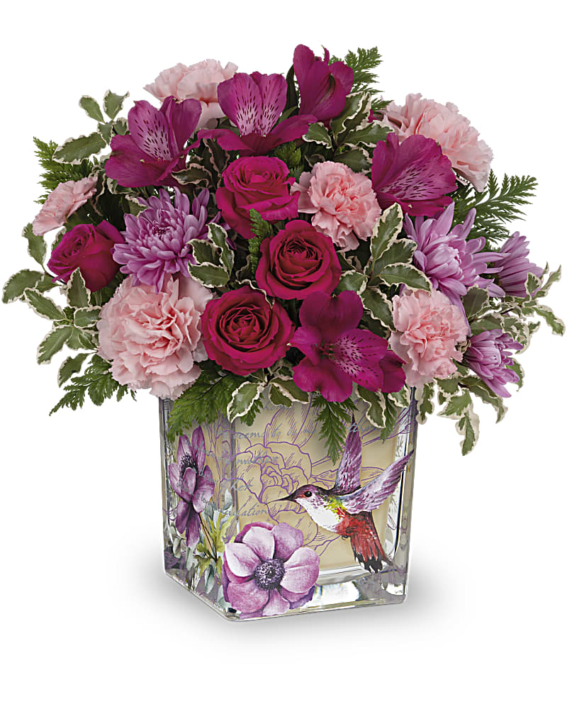 Pink and magenta bouquet in a square glass vase with hummingbird artwork