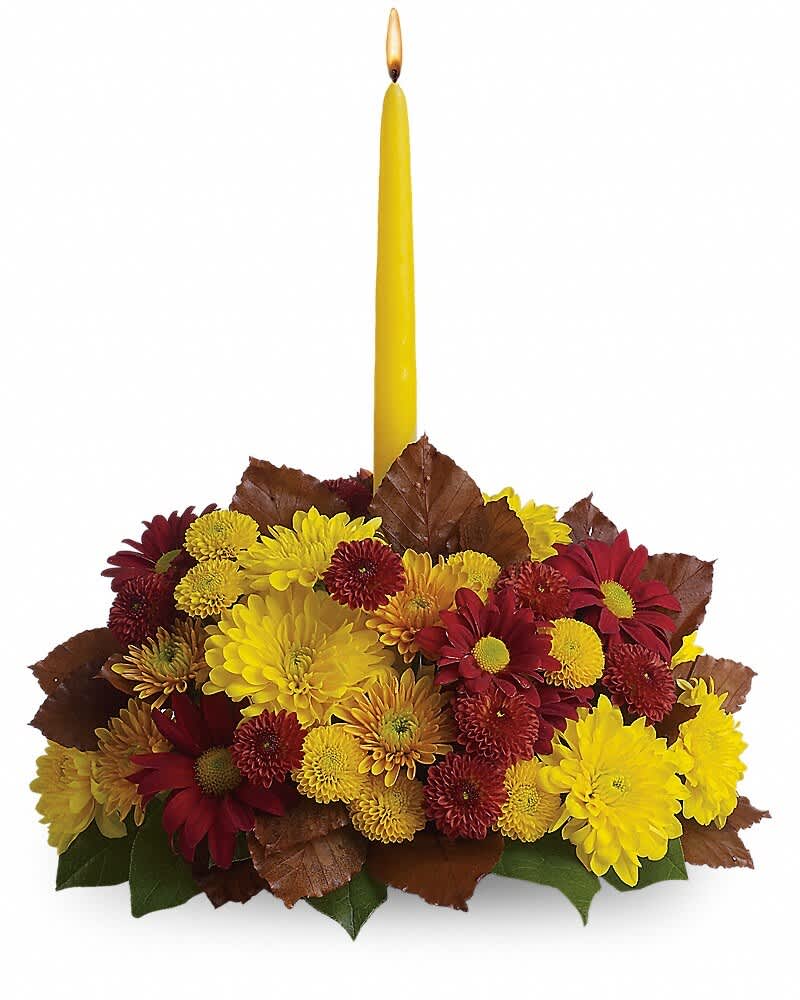 Yellow taper candle in a low arrangement of red and yellow chrysanthemums