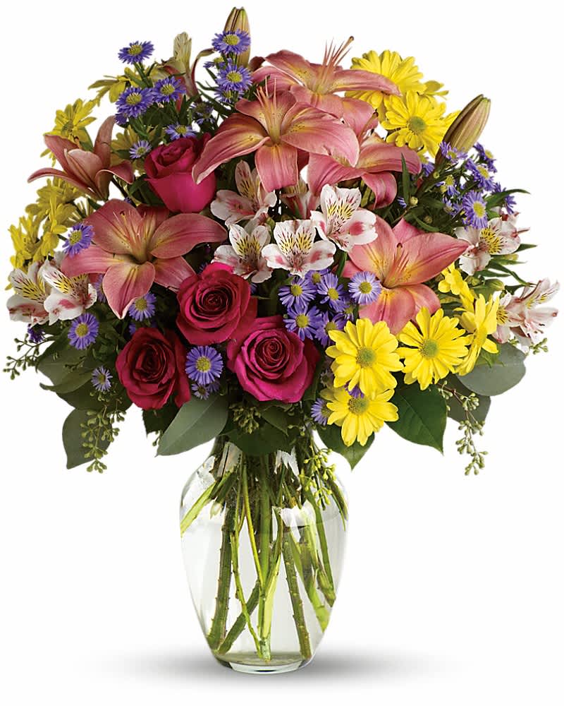 Mixed bouquet of pink lilies, roses, and yellow daisies in a glass vase