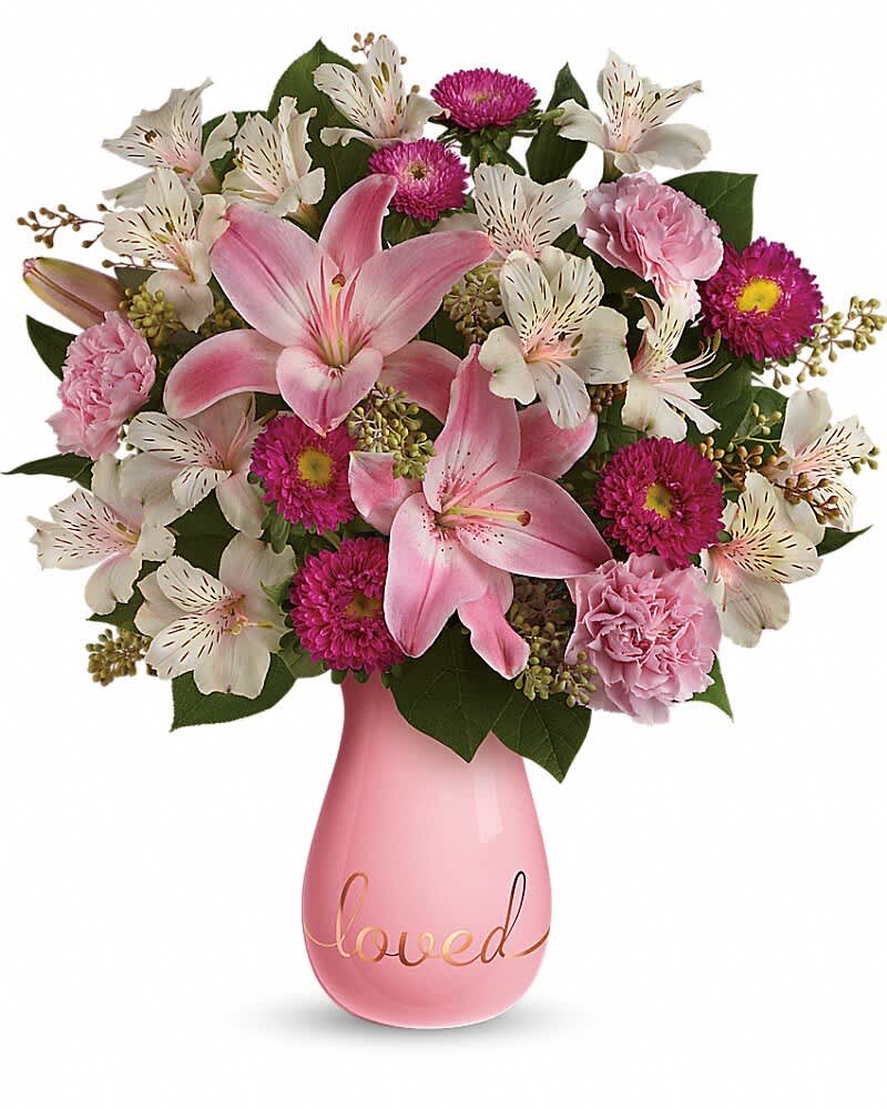 Pink lilies and mixed blooms in a pink vase with the word loved