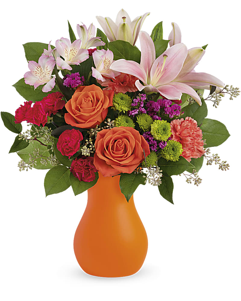 Orange vase with pink lilies, orange roses, and mixed flowers