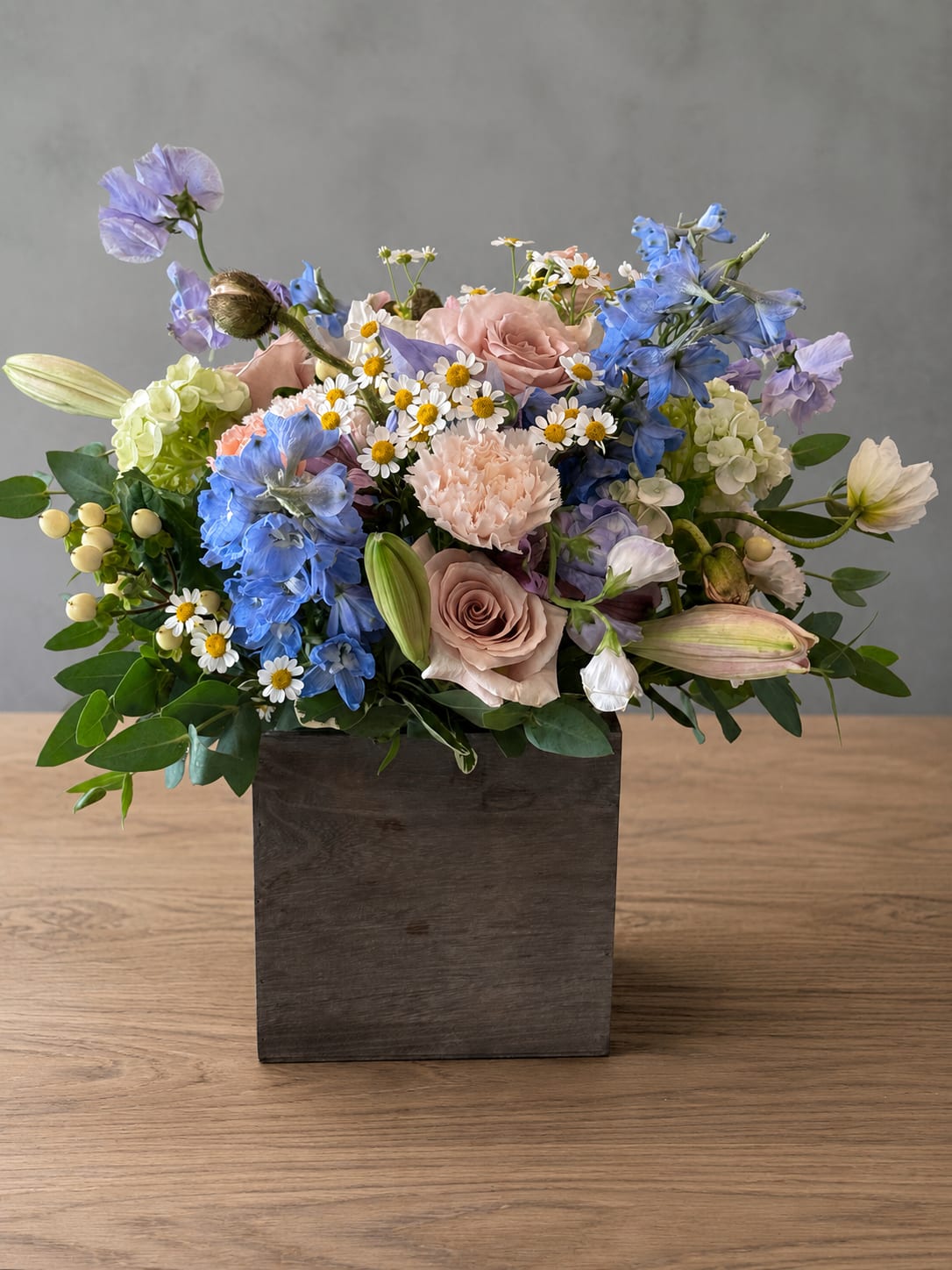 Sea Mist Box - A lush, garden-style arrangement designed with the freshest seasonal flowers available. Each piece is uniquely handcrafted in a rustic 6x6 wooden box, so flower varieties may vary while maintaining the same beautiful style and value.