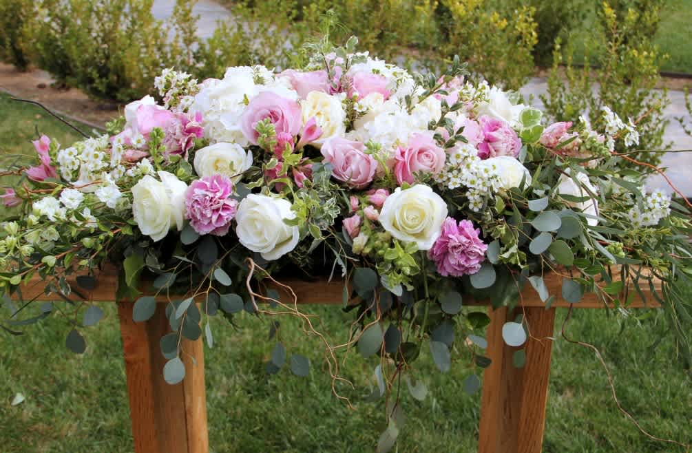 Large pink and white floral arrangement with roses on a wooden table
