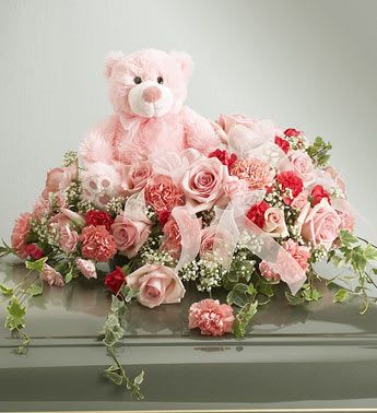 Pink teddy bear surrounded by pink and red flowers