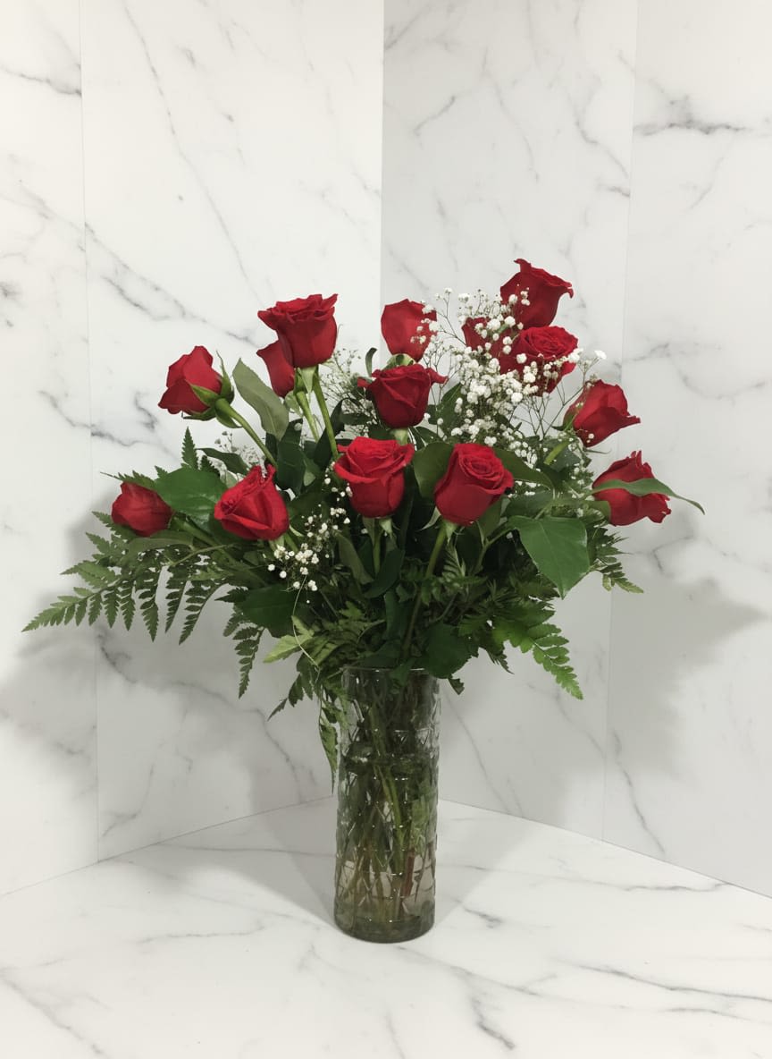 Vase of Roses - Timeless, elegant, and full of romance. this stunning arrangement features freash, velvety 12 roses beautifully displayed in a clear glass vase. Combined with baby breath and lush green foliage. Para cualquier edad, elegante y lleno de romance, este bonito arreglo fresco de 12 rosas hermosas en una vasija de cristal. Combinadas con las flores aliento de bebe y foliaje verde