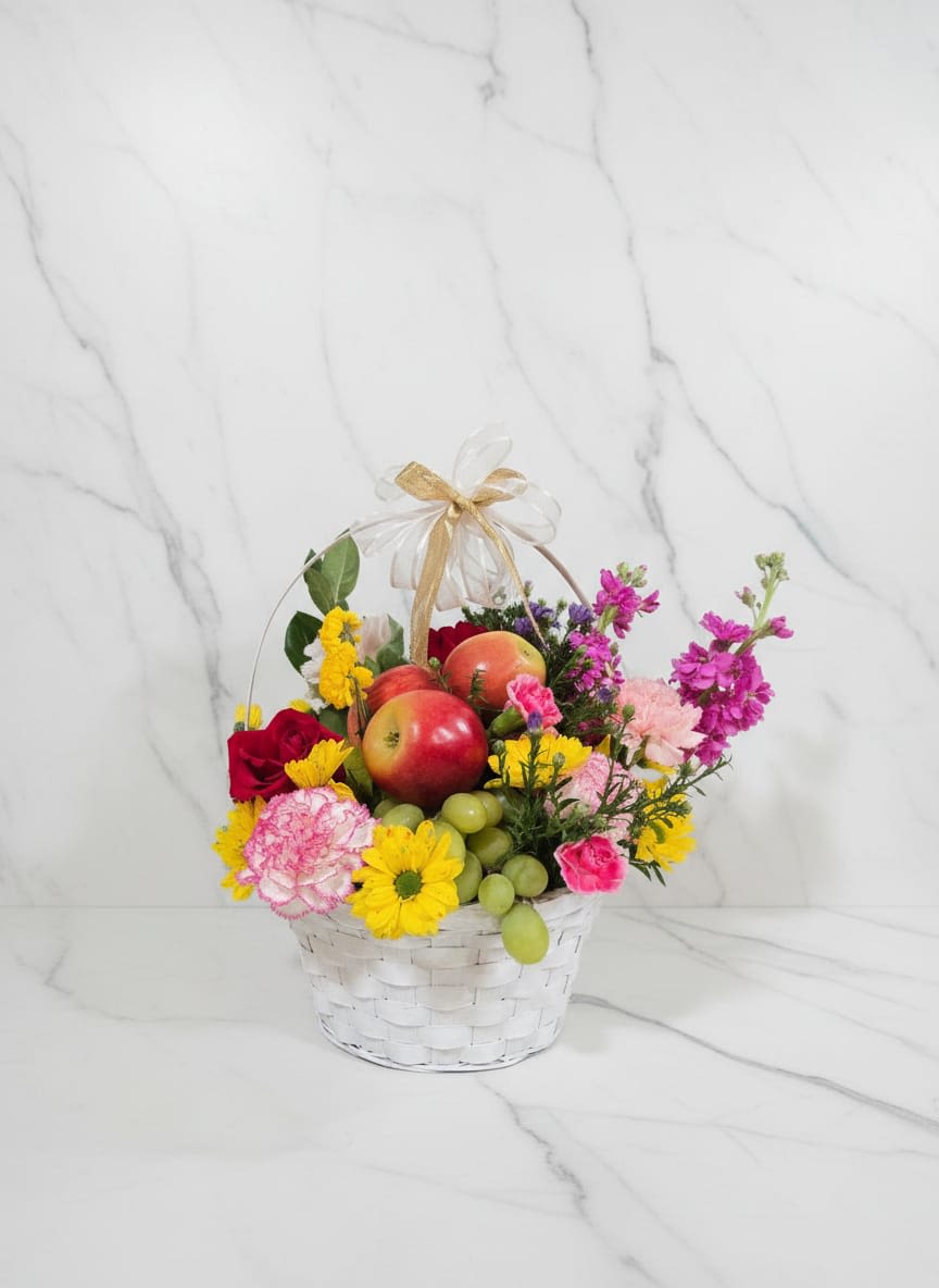 Harvest Bloom Basket - The combination of fresh fruits and flowers. Fresh apple, pears, green grapes, roses, carnations, decorative greenery, seasonal filler flowers, decorative basket base, and a sheer ribbon. La combinación de frutas y flores frescas. Manzana fresca, manzanas verdes, uvas verdes. rosas, claveles, follaje decorativo, flores de relleno de temporada, base de cesta decorativa y un lazo transparente.