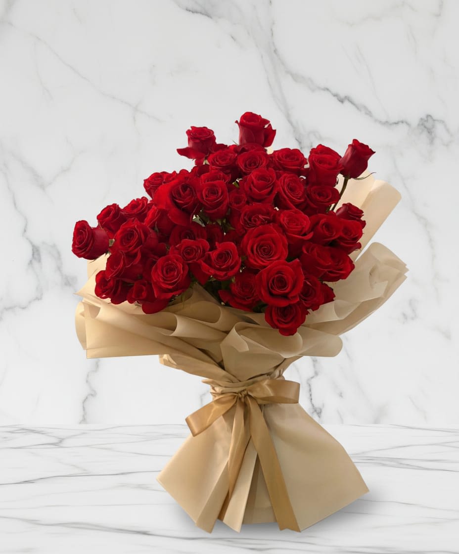 Crimson Romance Bouquet - A stunning bouquet of 35 red roses arranged in a full elegant design that symbolizes love, passion, and timeless romance. The vibrant roses are beautifully wrapped in soft neutral toned floral paper and finished with delicate ribbon, creating a refined and luxurious presentation. Un impresionante ramo de 35 rosas rojas dispuestas en un diseño completo y elegante que simboliza el amor, la pasión y el romance eterno. Las vibrantes rosas están bellamente envueltas en papel floral de tonos neutros y suaves, y terminadas con una delicada cinta, creando una presentación refinada y lujosa.