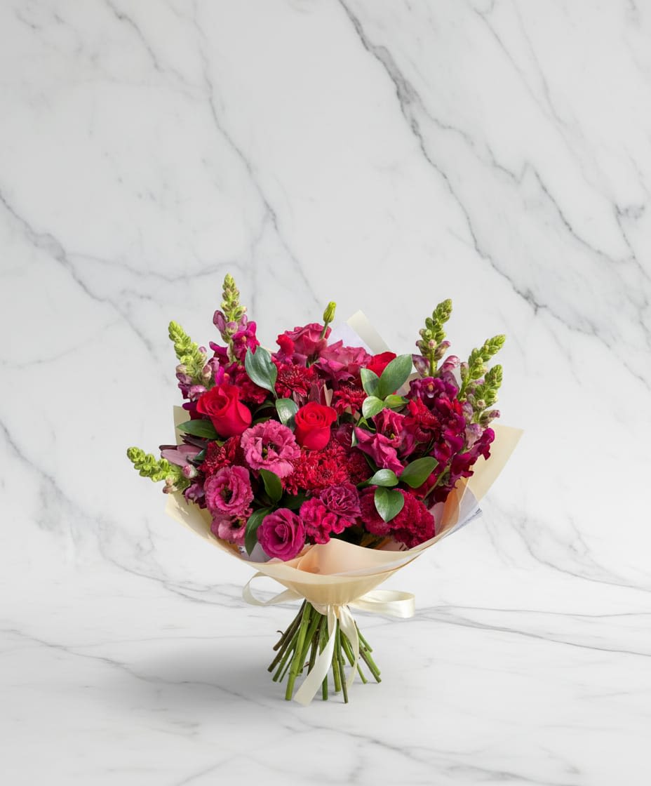 Magenta Love Bouquet - A vibrant and elegant bouquet featuring rich shades pink and magenta blooms arranged in soft, romantic style. This beautiful arrangement combines delicate roses and seasonal flowers with fresh greenery to create a full and eye catching bouquet. It includes pink roses, magenta or pink carnations, light pink filler flowers, and foliage. Un ramo vibrante y elegante que presenta ricos tonos de flores rosas y magenta dispuestas en un estilo suave y romántico. Este hermoso arreglo combina delicadas rosas y flores de temporada con vegetación fresca para crear un ramo completo y llamativo. Incluye rosas rosas, claveles magenta o rosas, flores de relleno color rosa claro y follaje.