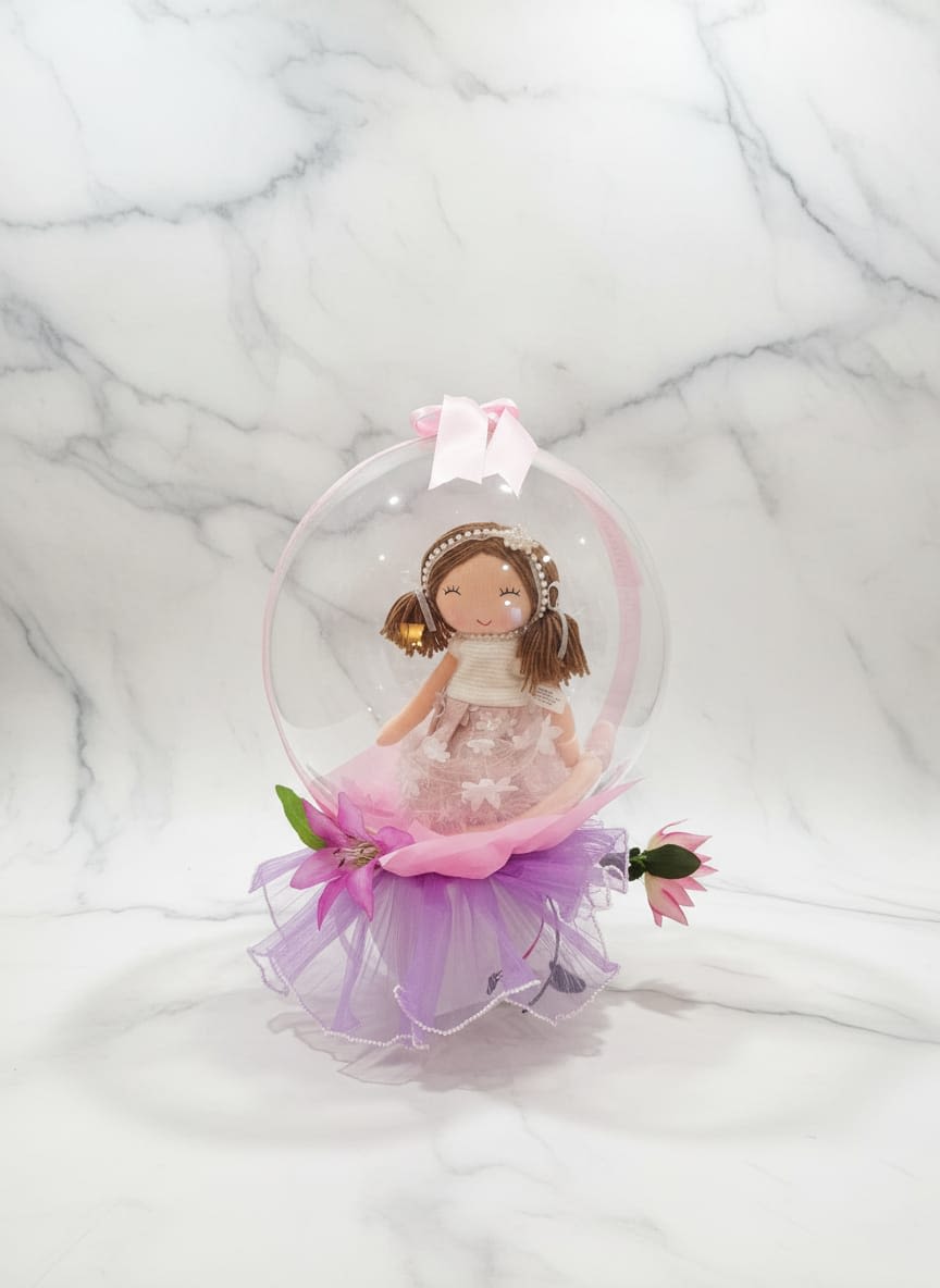Doll in a Dome - A hadcrafted arrangement including plastic flowers, inside the buble is a doll, the arrangement can change according to the client and the materials in store. Un arreglo hecho a mano que incluye flores de plástico, dentro de la burbuja hay una muñeca, el arreglo puede cambiar según el cliente y los materiales disponibles en la tienda.
