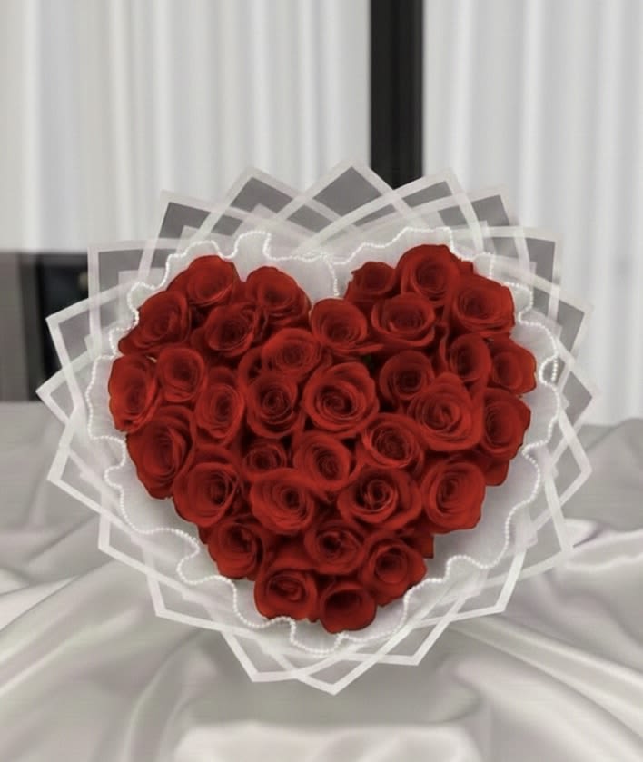 Heart-shaped bouquet of red roses wrapped in white paper