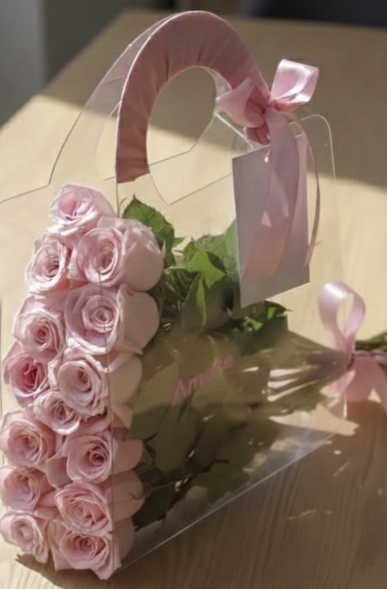 Pink roses in a clear gift box with a ribbon handle