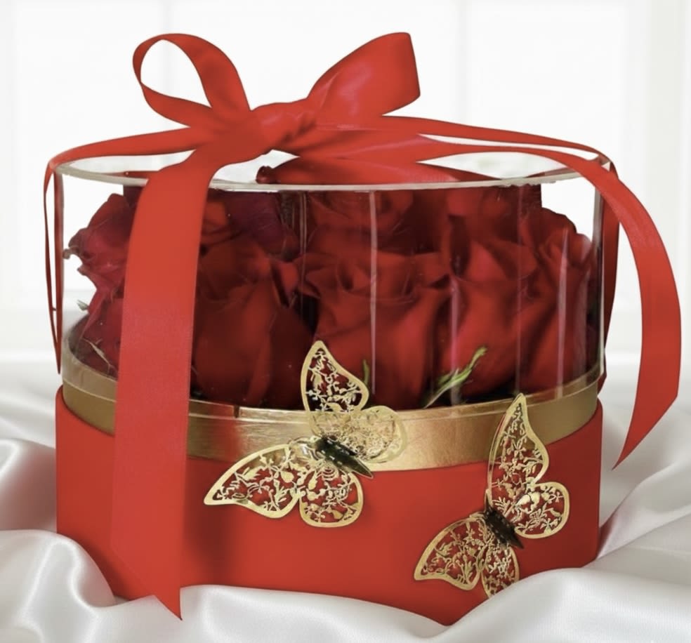 Red roses in a clear round gift box tied with a red ribbon