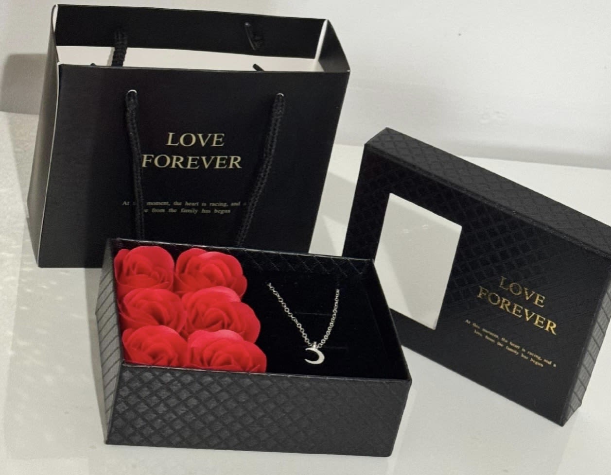 Black gift boxes with red roses and a crescent necklace