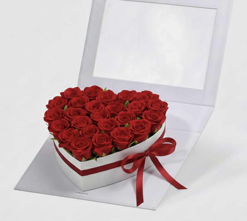 Heart-shaped box filled with red roses and tied with a red ribbon