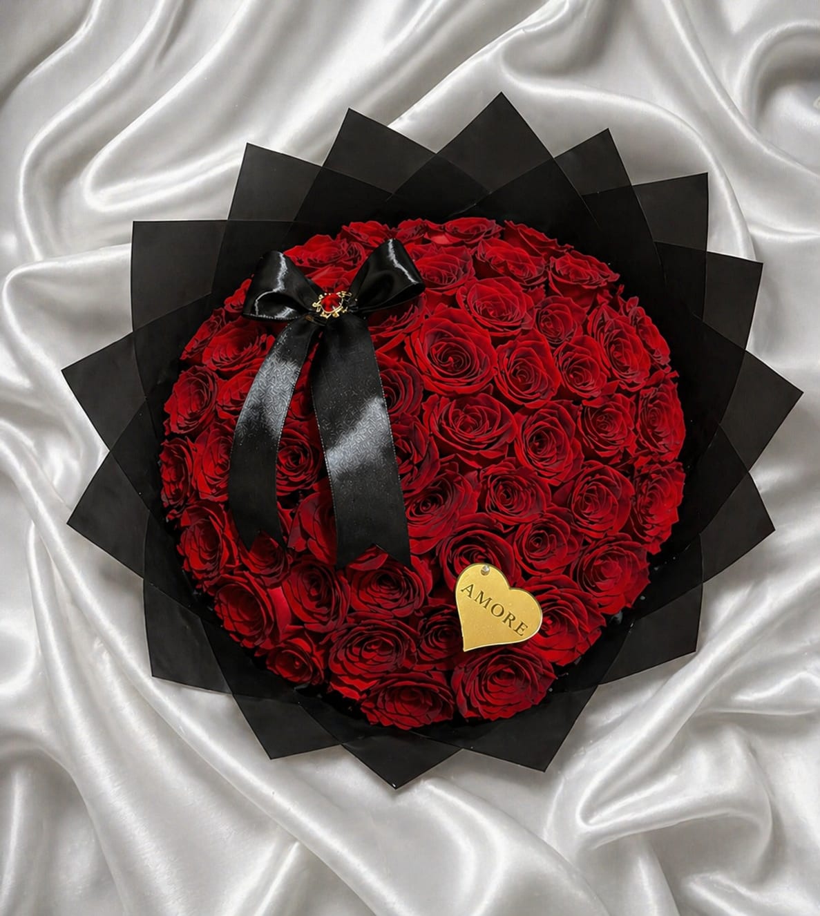 Luxury Red Rose Bouquet – Signature Collection - The Luxury Red Rose Bouquet – Signature Collection is a bold and refined floral statement designed with premium fresh roses and finished in a modern structured black wrap with an elegant satin bow.  This design combines classic romance with contemporary presentation, creating a striking and sophisticated look. The layered geometric wrapping enhances depth and contrast, allowing the roses to stand out with dramatic elegance.  Perfect for anniversaries, romantic surprises, milestone celebrations, and grand gestures, this bouquet is available in multiple rose counts to match the occasion and level of impact desired.  Rose color may vary based on availability. 