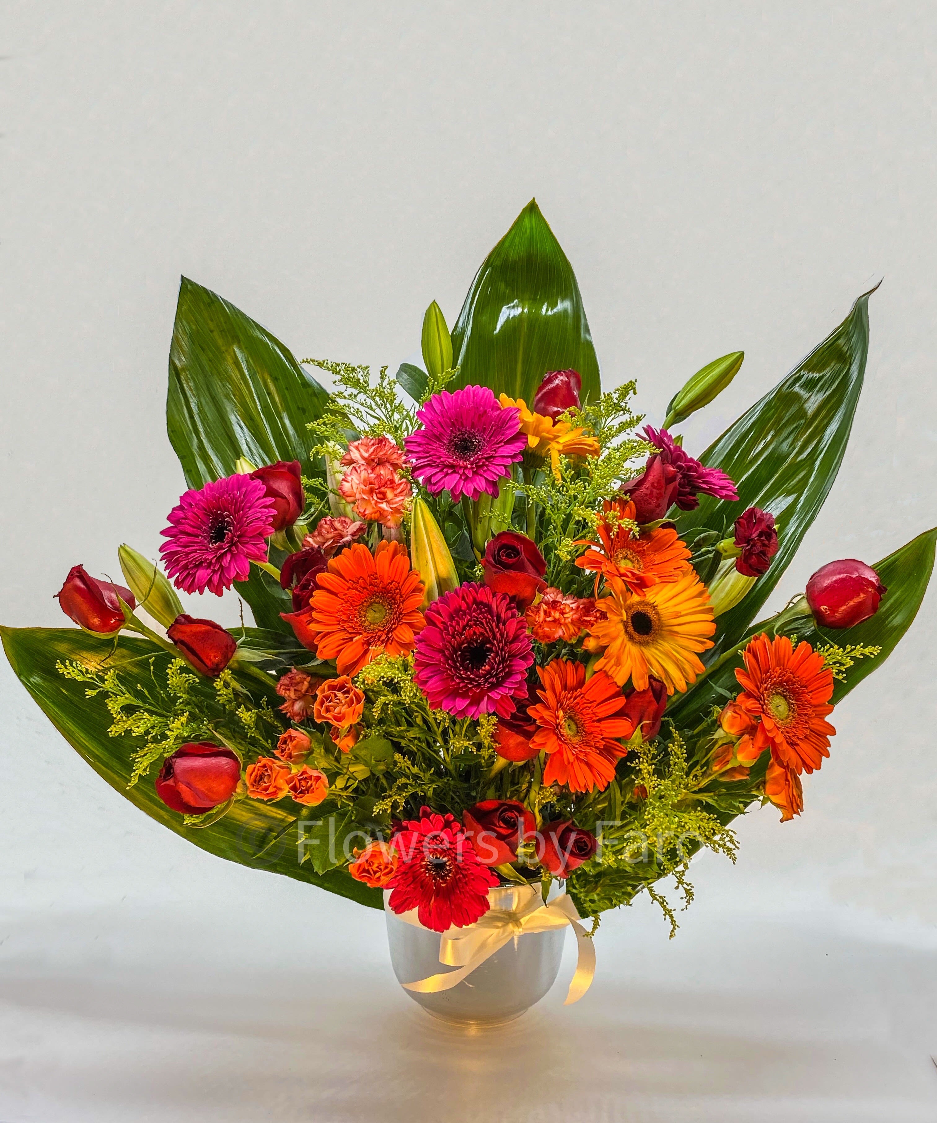 Bright mixed bouquet in a glass vase with red, orange, and pink flowers