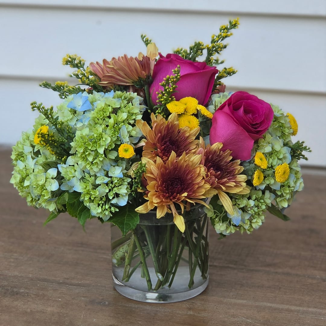Pink roses and mixed blooms in a clear glass vase