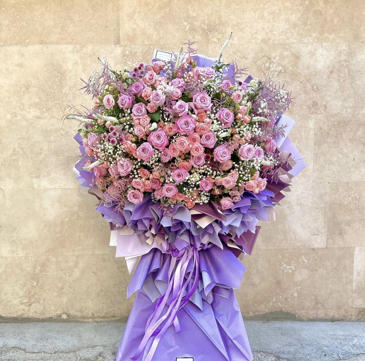 Large bouquet of pink roses wrapped in purple paper