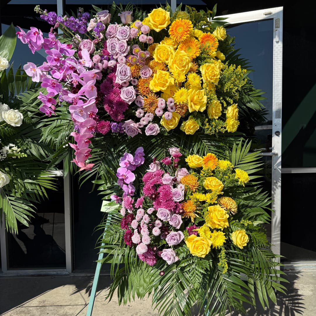 Large standing floral spray with yellow, pink, and purple flowers