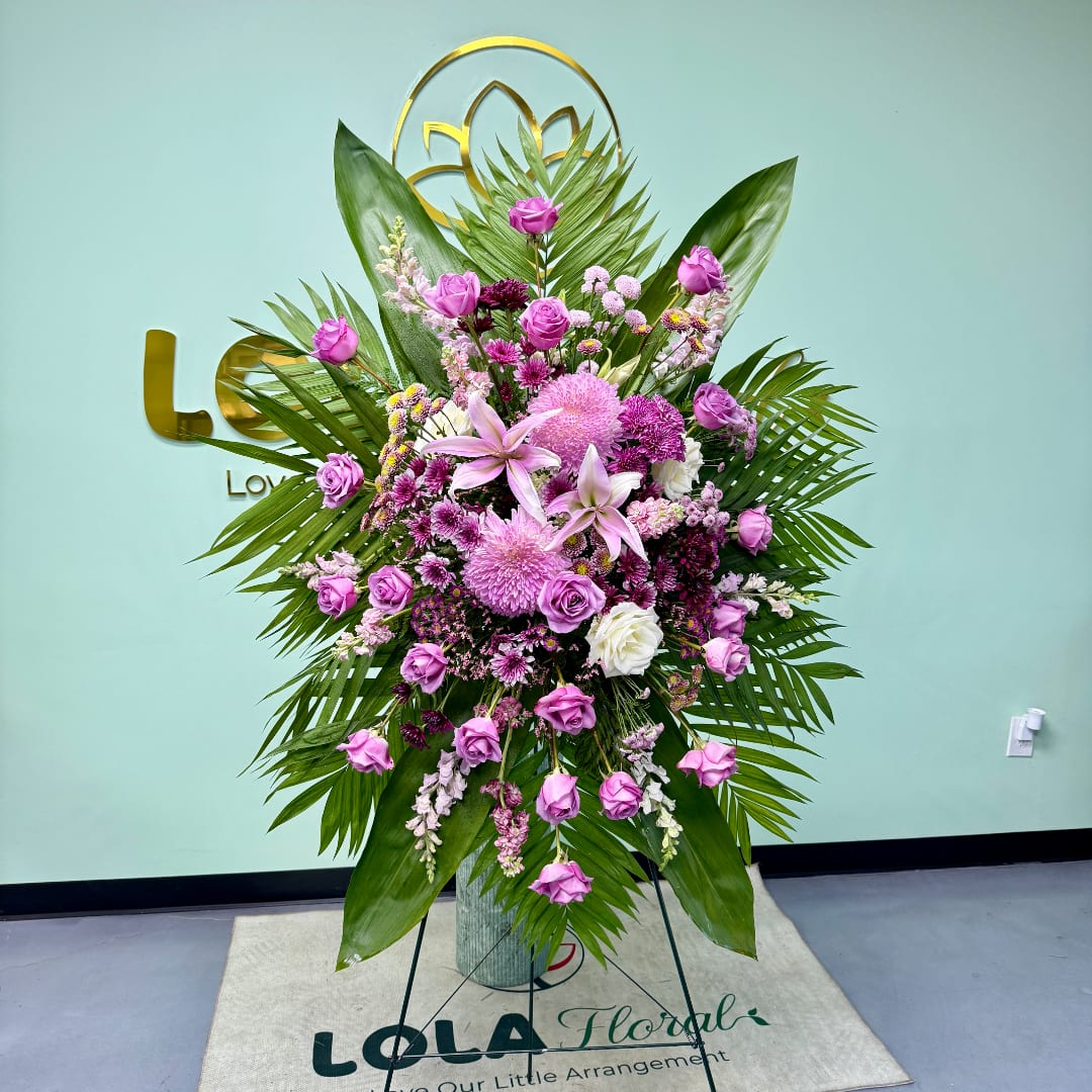 Tall pink and purple floral standing arrangement with palm leaves in a vase