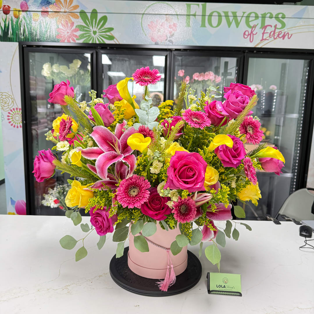 Pink and yellow mixed flower arrangement in a blush hatbox
