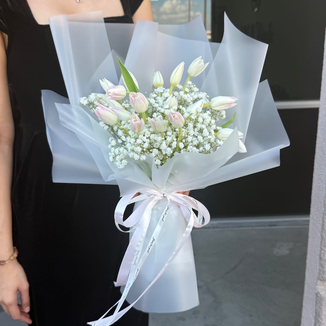 Bouquet of pale pink and white tulips wrapped in translucent paper