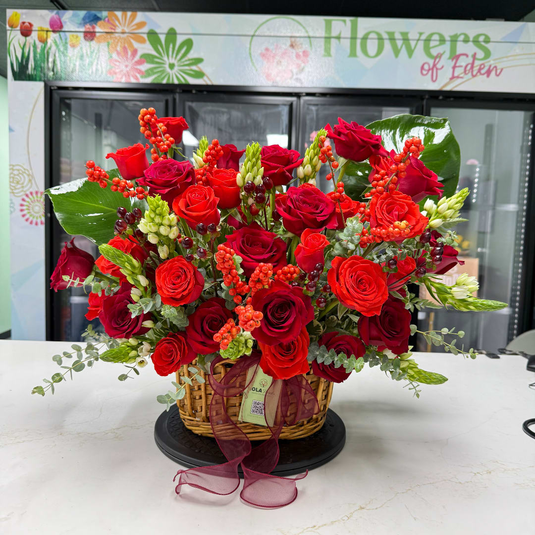 Basket arrangement of red roses with berries and ribbon