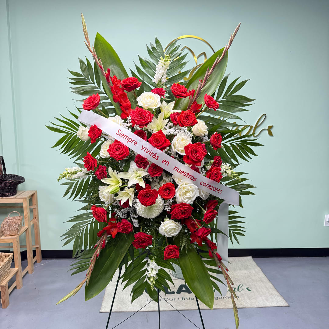 Standing floral spray of red and white roses with a condolence ribbon