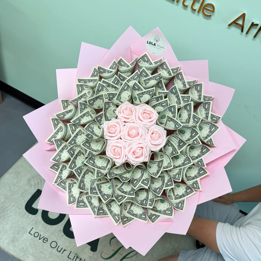 Bouquet of pink roses surrounded by folded dollar bills