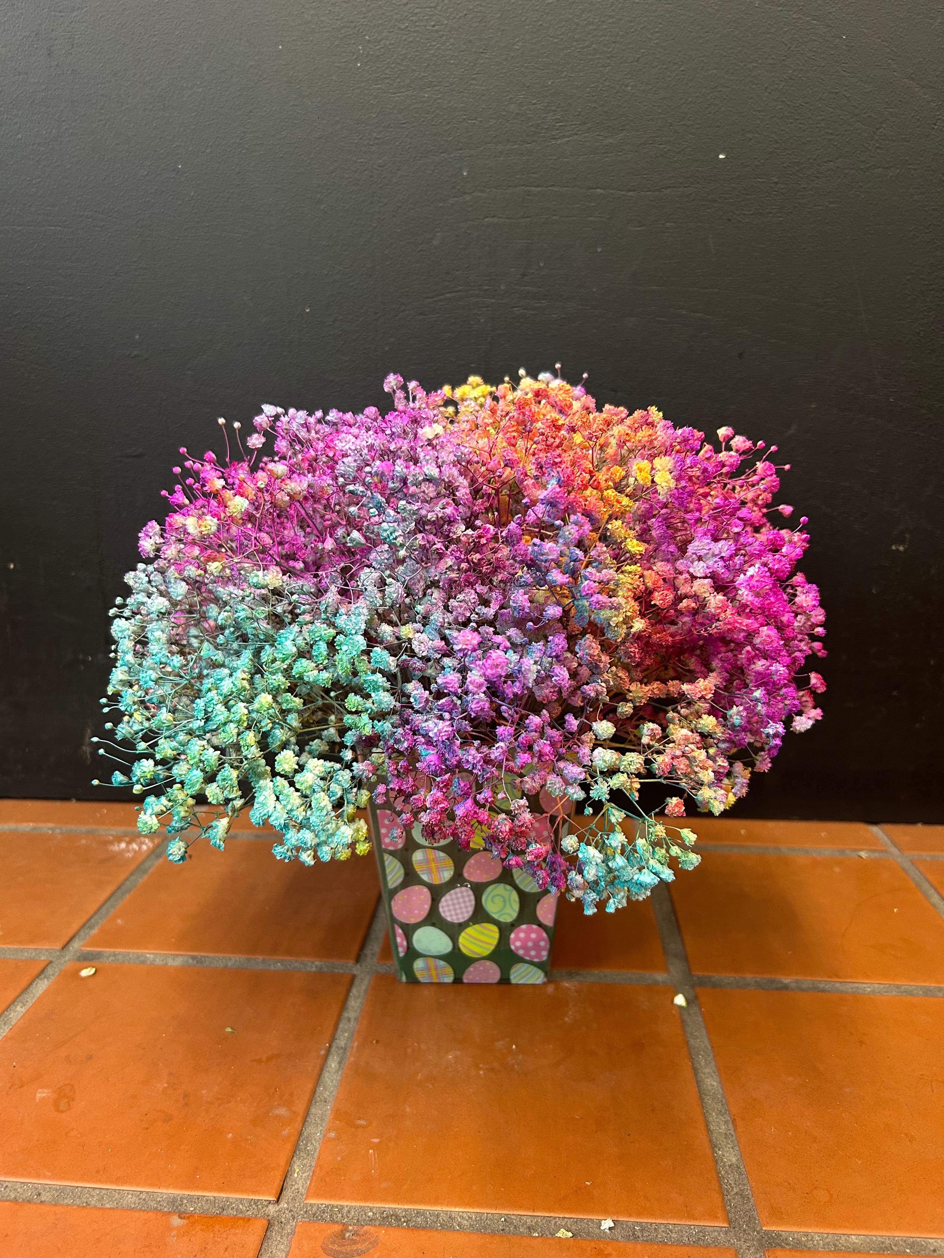 Compact arrangement of rainbow-dyed tiny blooms in a patterned square container