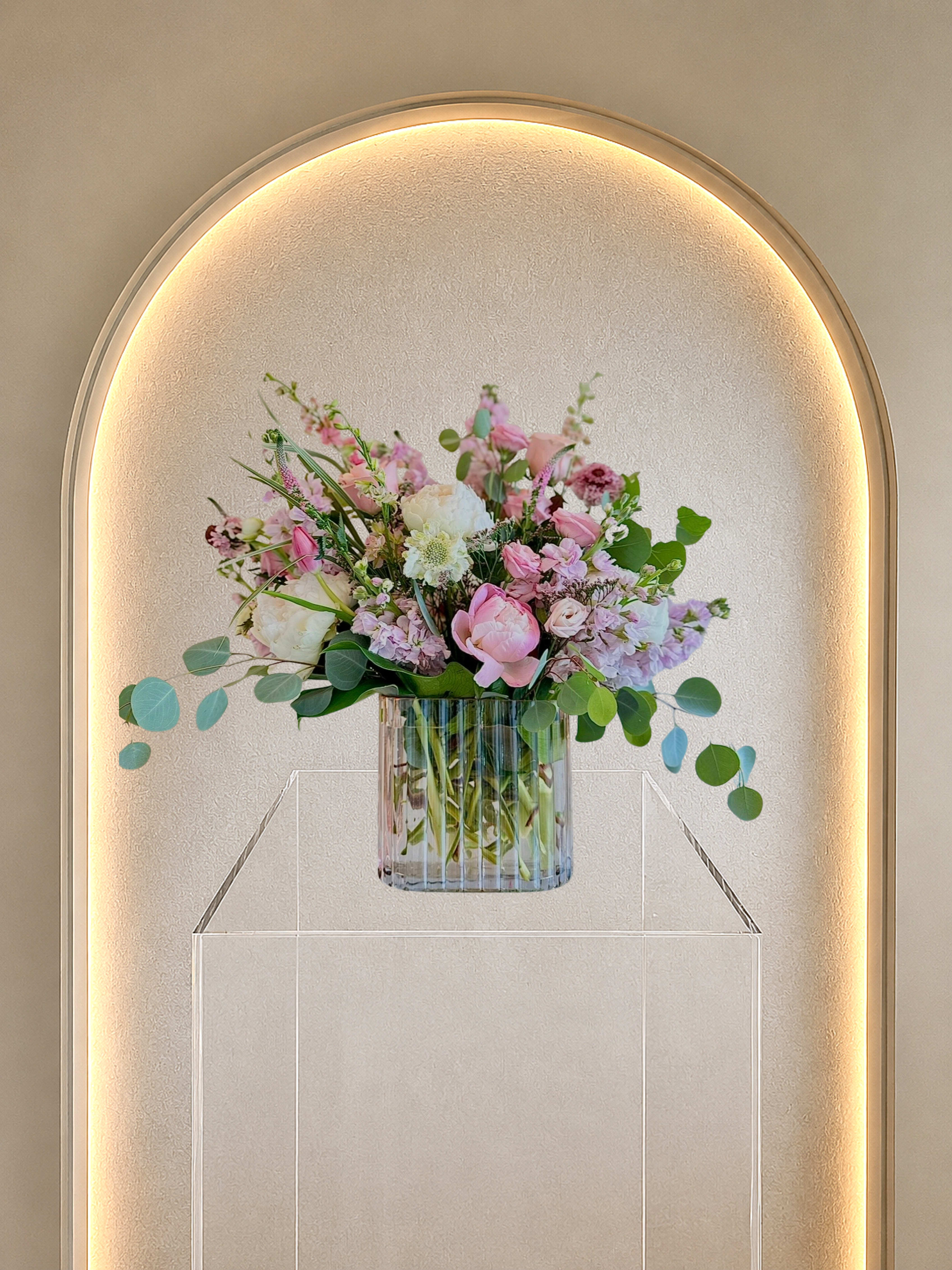Pink Elegance - A loaded arrangement with fresh flowers in a stunning pink ribbed glass vase, designed with a mix of heights, textures and colors 