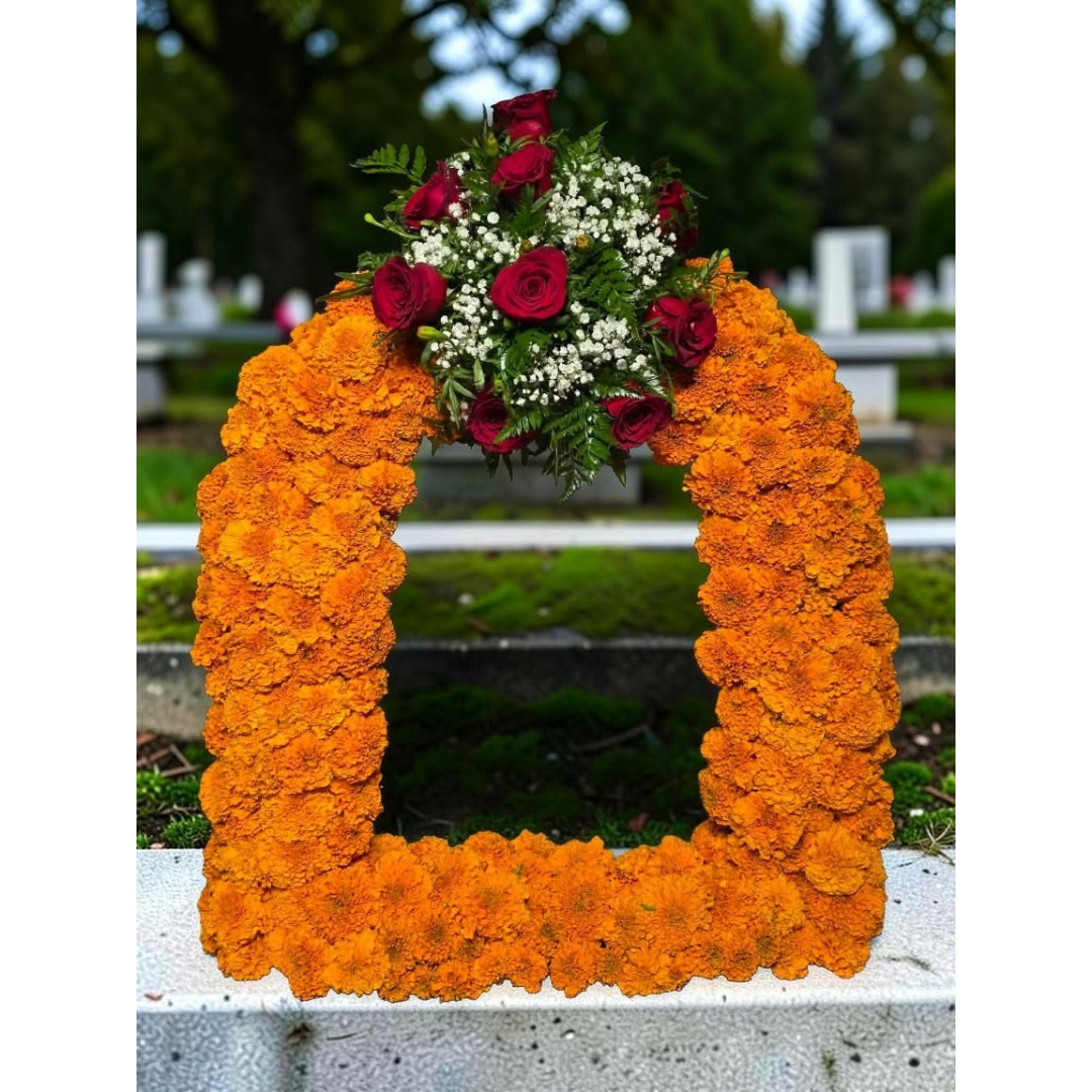 Orange marigold funeral wreath with red roses and white filler flowers