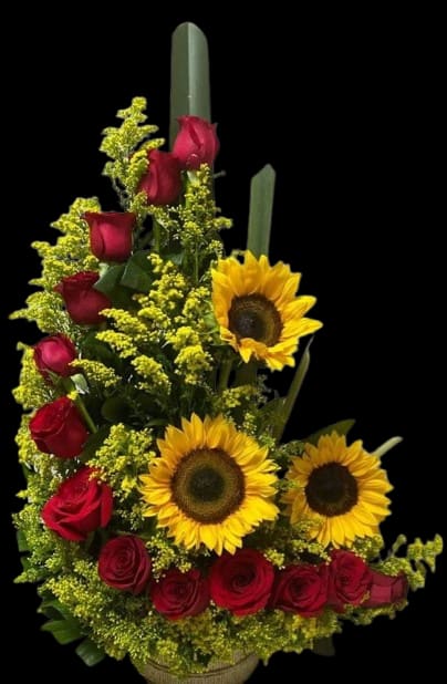 Summer Love - A tall, tiered arrangement of deep red roses and bright yellow sunflowers creates a bold, cheerful statement for birthdays, congratulations, or a romantic everyday gift. The structured, formal silhouette makes the recipient feel truly celebrated-she'll notice the confident contrast between the velvety red roses and the sunny, open faces of the sunflowers the moment it arrives.  Small yellow filler flowers are woven throughout the composition for texture and visual density, set in a classic basket that adds warmth and natural charm. The red, yellow, and green palette reads vibrant and uplifting from every angle; the arrangement's height and layered build make it an ideal centerpiece or a standalone focal gift. Care: keep in fresh water, away from direct heat, and refresh water daily to extend bloom life.