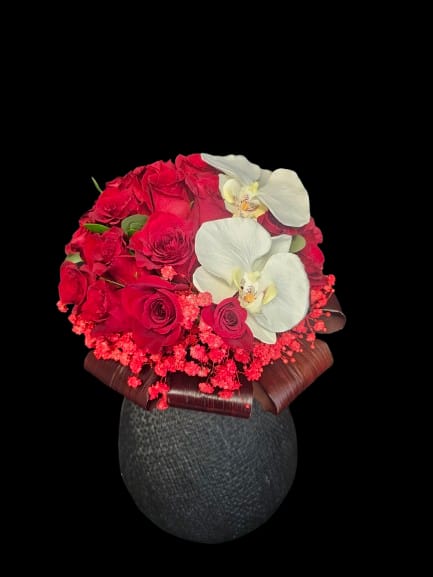 Red roses with white orchids in a dark vase