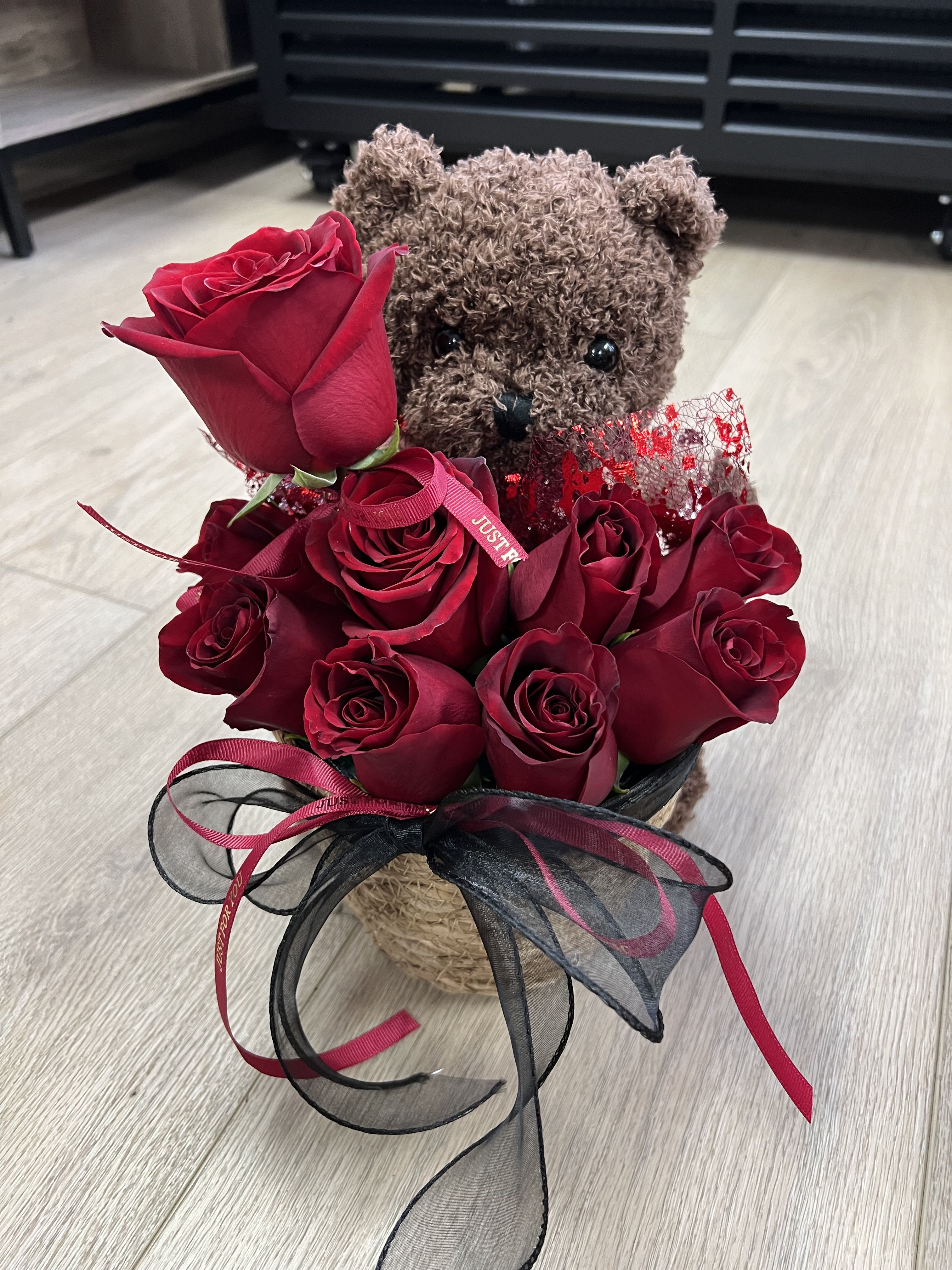 Be Mine, Teddy - A charming teddy bear holding a bouquet of vibrant red roses adorned with delicate ribbons.