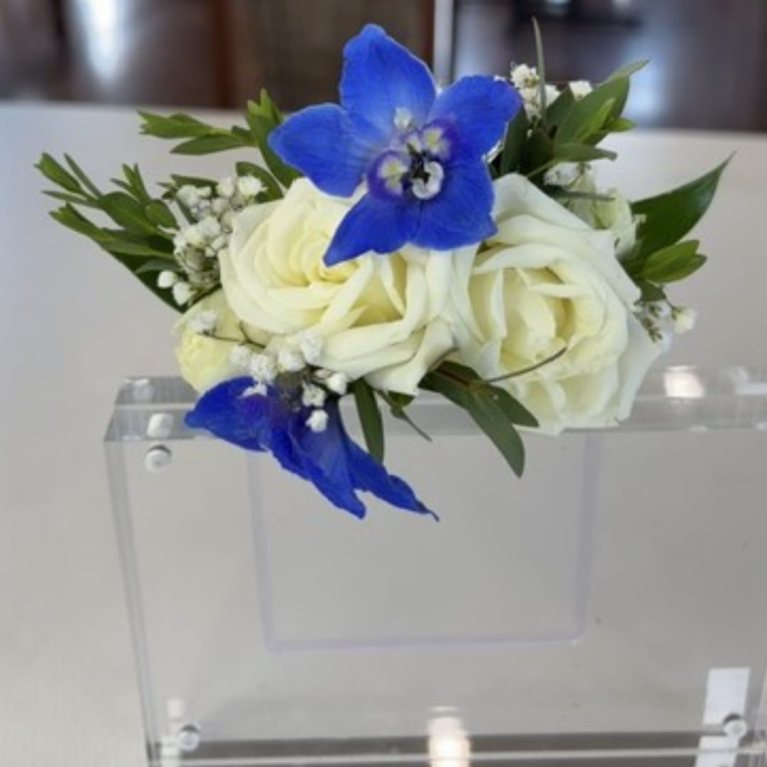 White roses with blue orchids in a clear acrylic holder