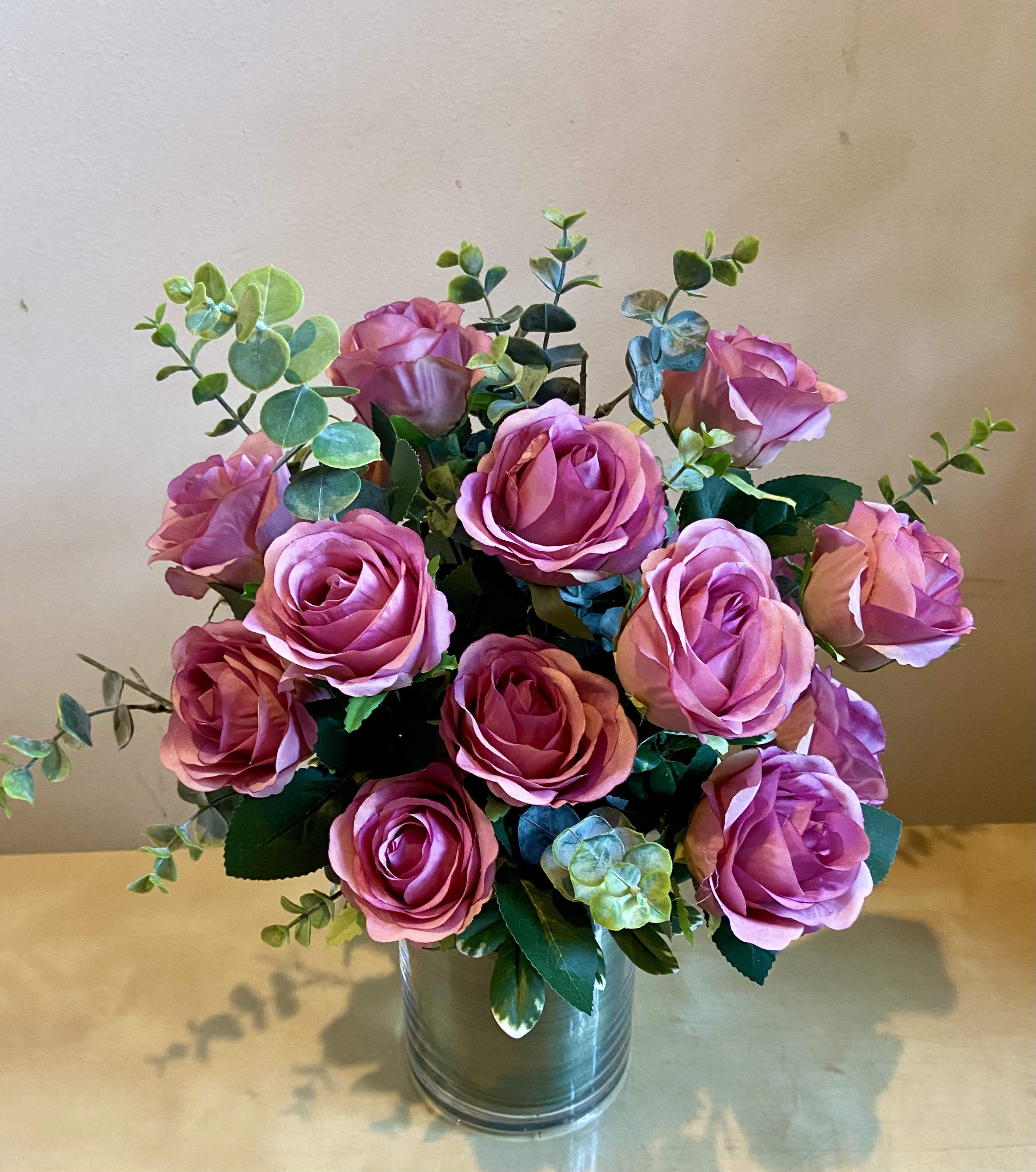 Pink roses arranged in a metal vase with eucalyptus
