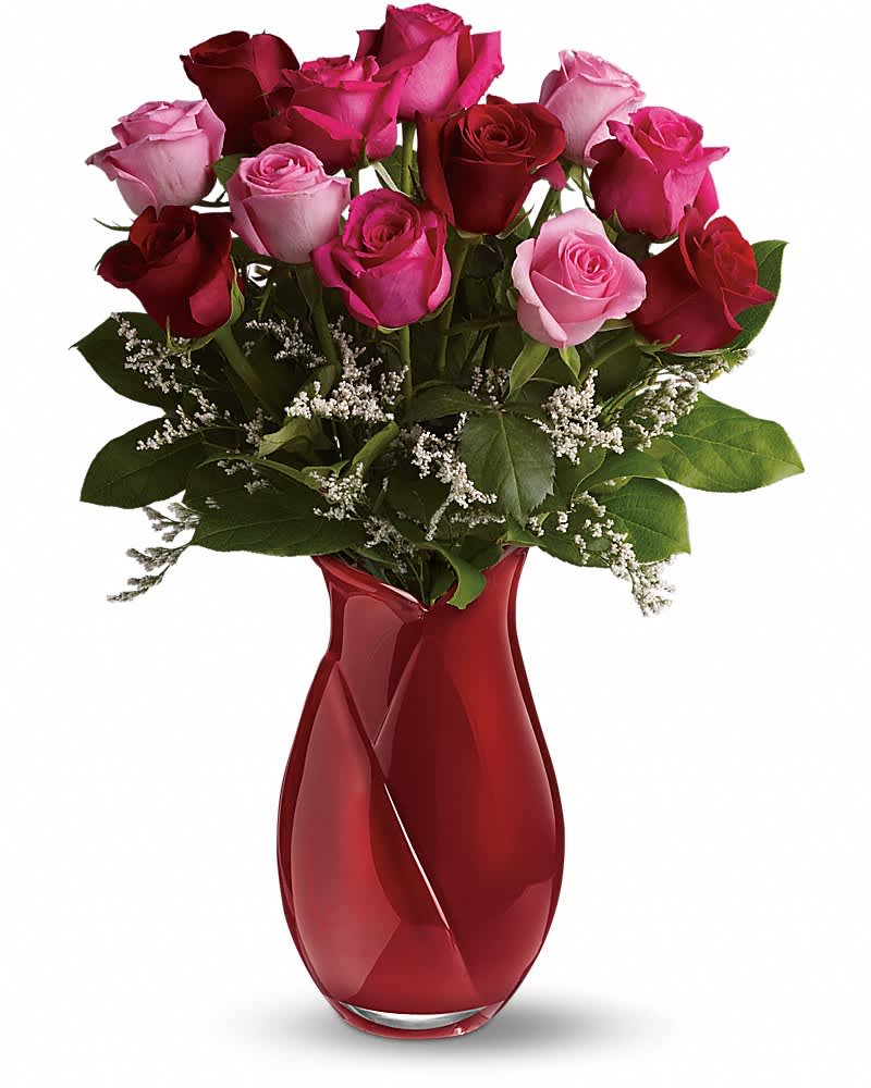 Red and pink rose bouquet in a red glass vase with white filler flowers