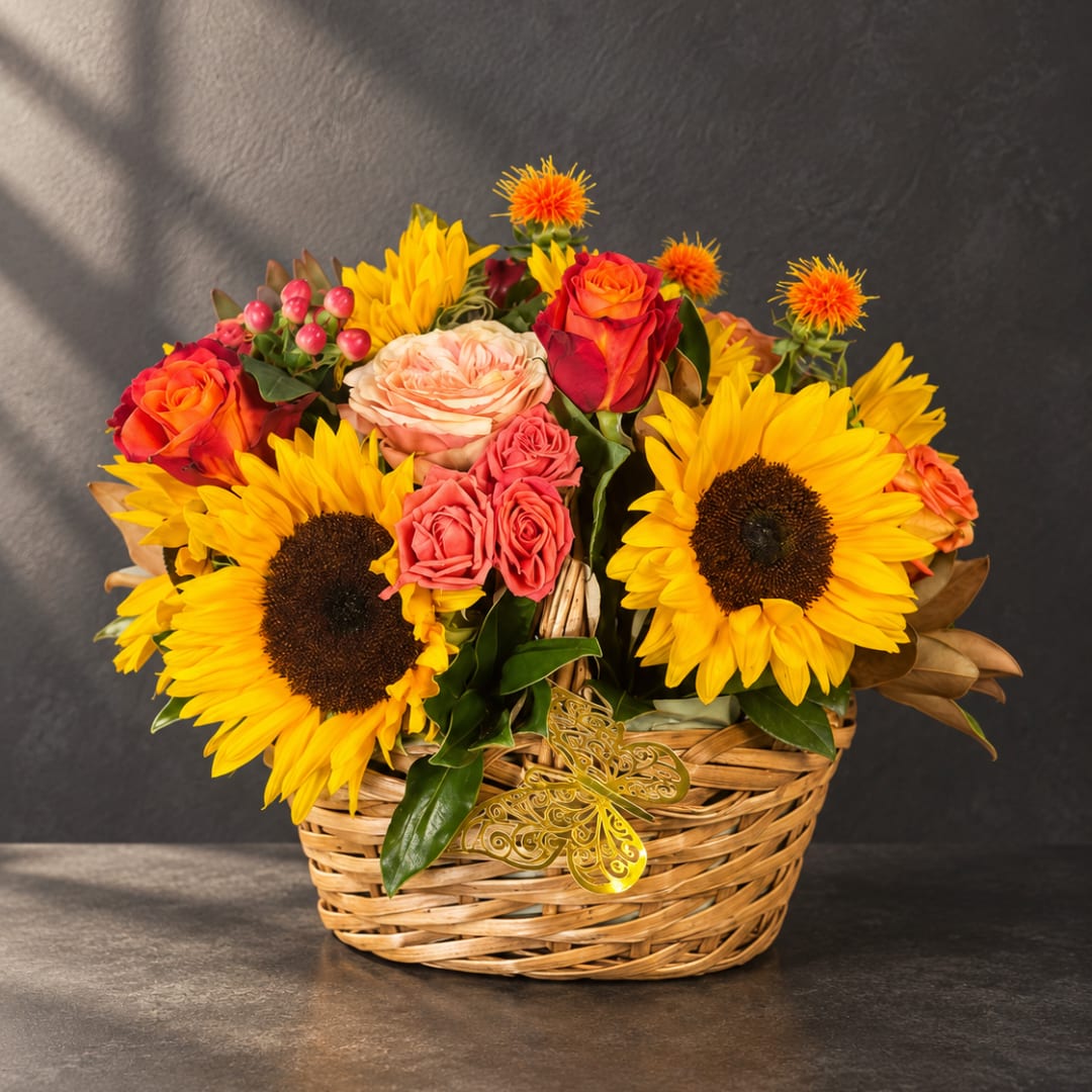 Basket arrangement with sunflowers, roses, and small orange blooms