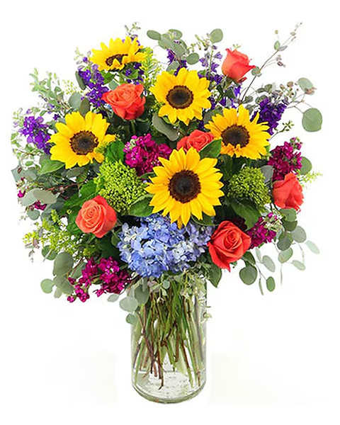 Bouquet of sunflowers, coral roses, and purple flowers in a glass vase