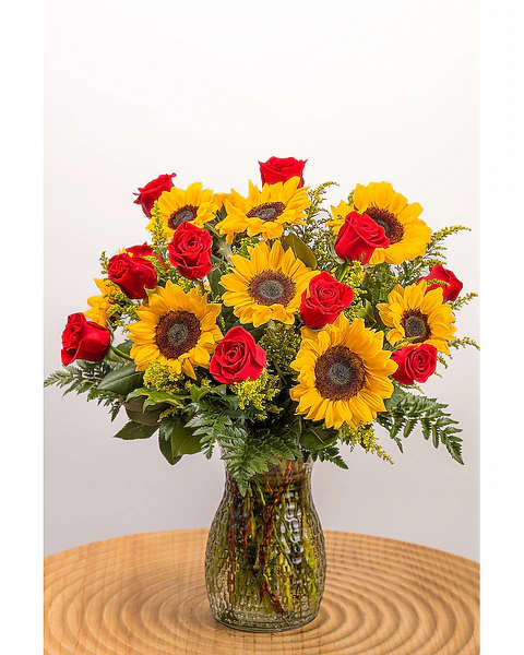 Sunflowers and red roses arranged in a glass vase