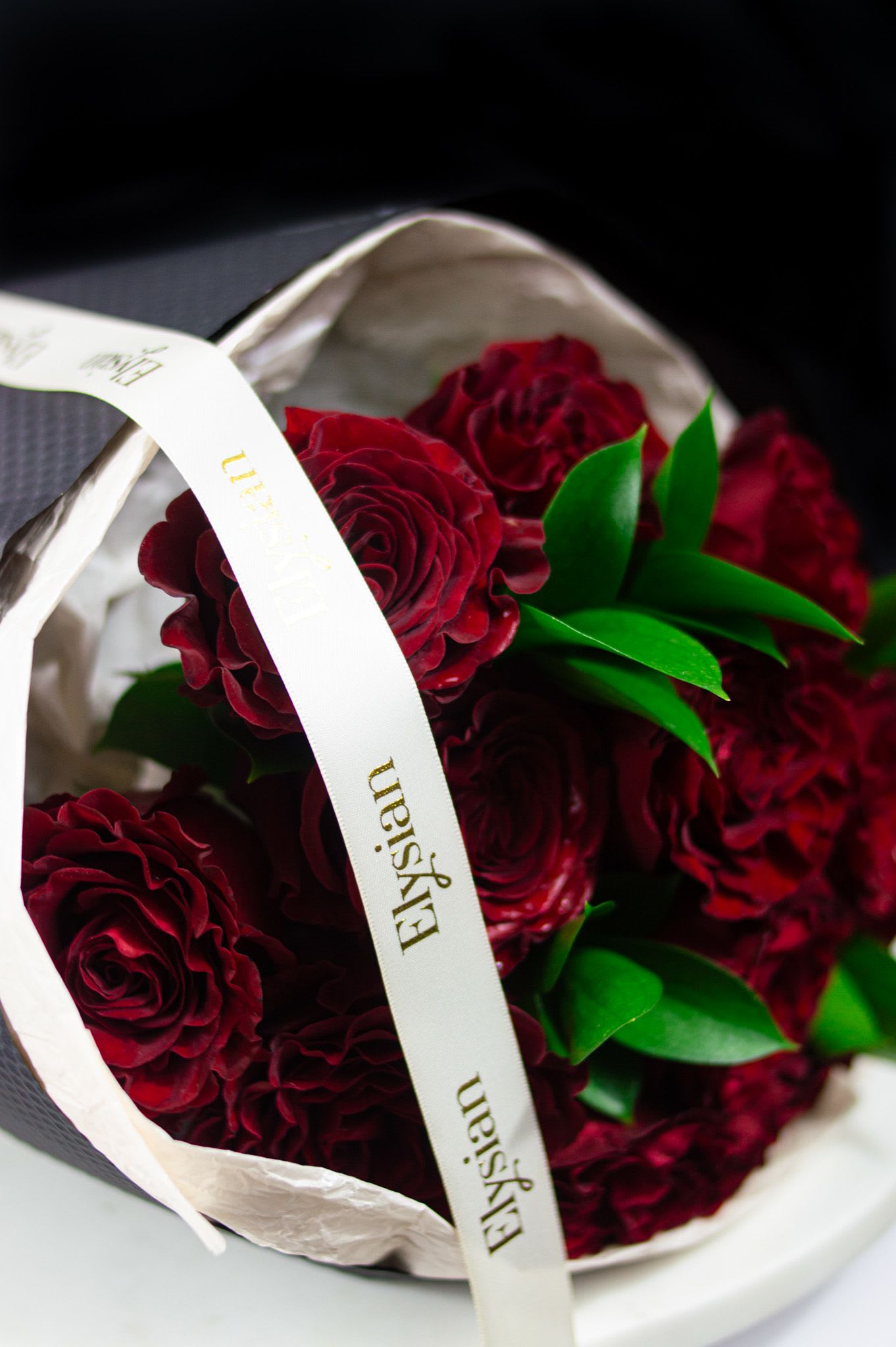 Midnight Heart - Classic, powerful, and undeniably romantic. Midnight Heart is a striking bouquet of deep red roses, tightly gathered to create a rich, velvety statement. Accented with fresh green foliage and wrapped in sleek black paper, this design embodies passion, strength, and timeless elegance.  Designed for grand gestures and unforgettable moments, Midnight Devotion is perfect for declarations of love, anniversaries, or when you want to leave a lasting impression.  Because some loves are bold, deep, and eternal. ️  Disclaimer: Due to the seasonal nature of flowers, we select the freshest blooms available. Flower varieties may vary slightly, but we always preserve the color palette, style, and overall aesthetic shown.